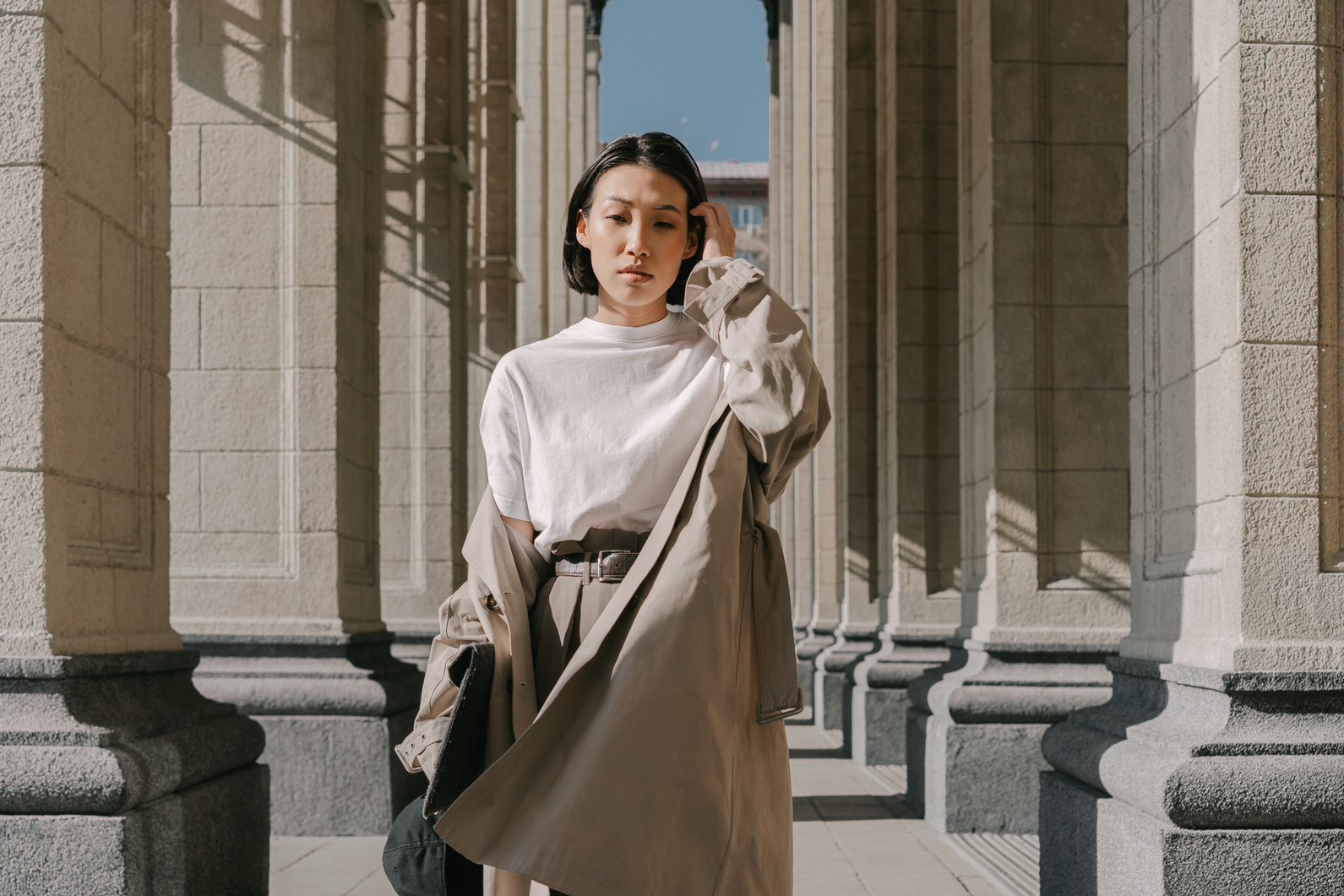 Woman in Fashionable Outfit Standing Between Columns